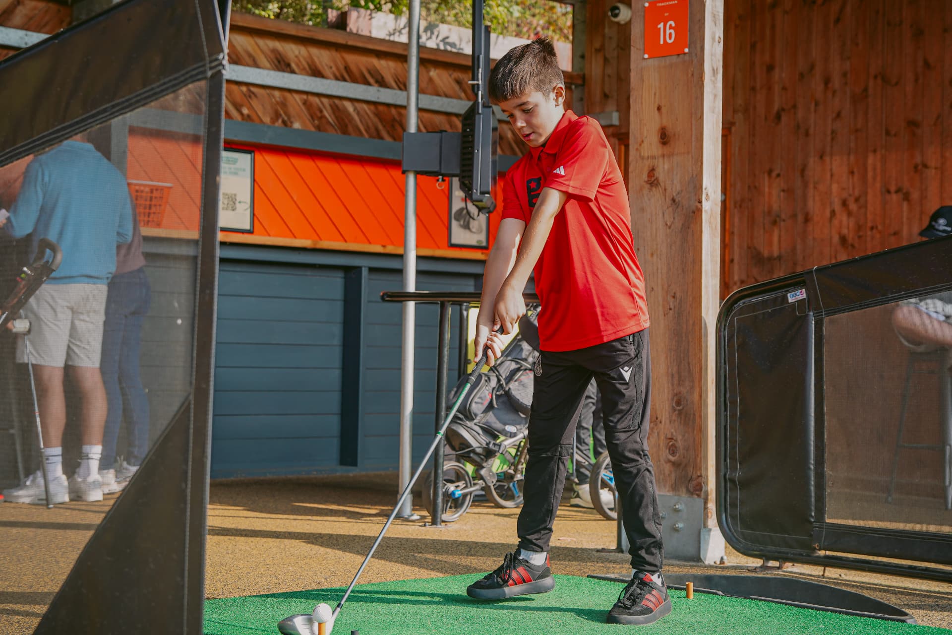 Young golfers practising in the driving range bays at a Golfstars venue