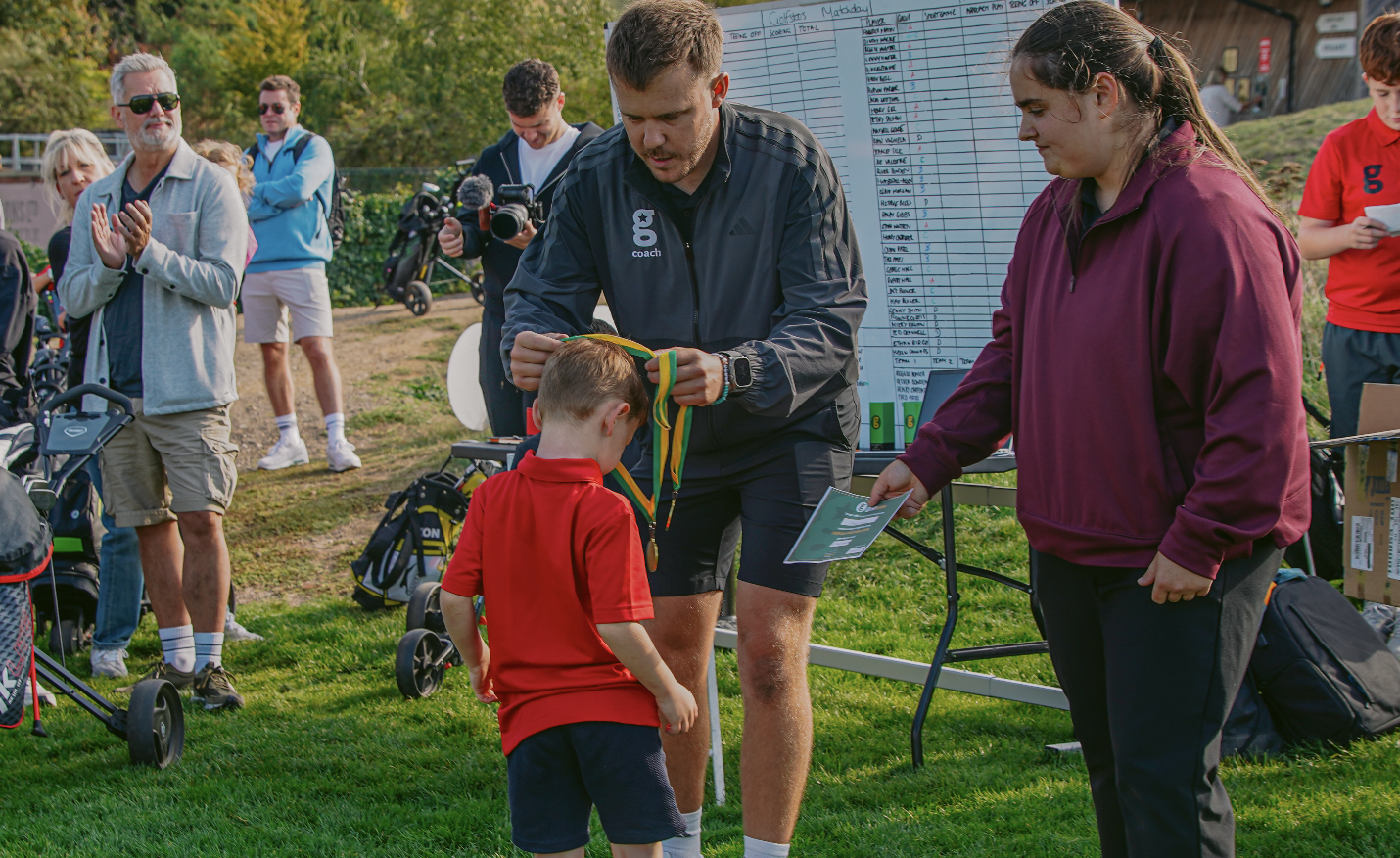 Golfstars coach presenting a medal to a young golfer at a matchday