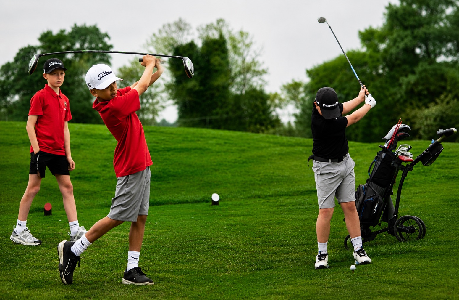 Junior golfers hitting tee shots during a league round