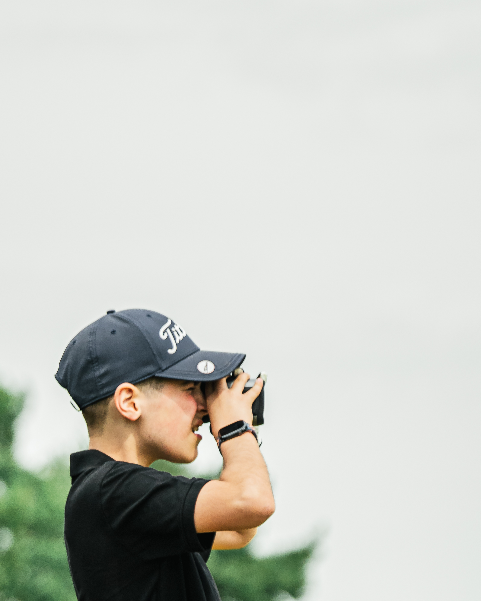Junior golfer using a rangefinder on the course