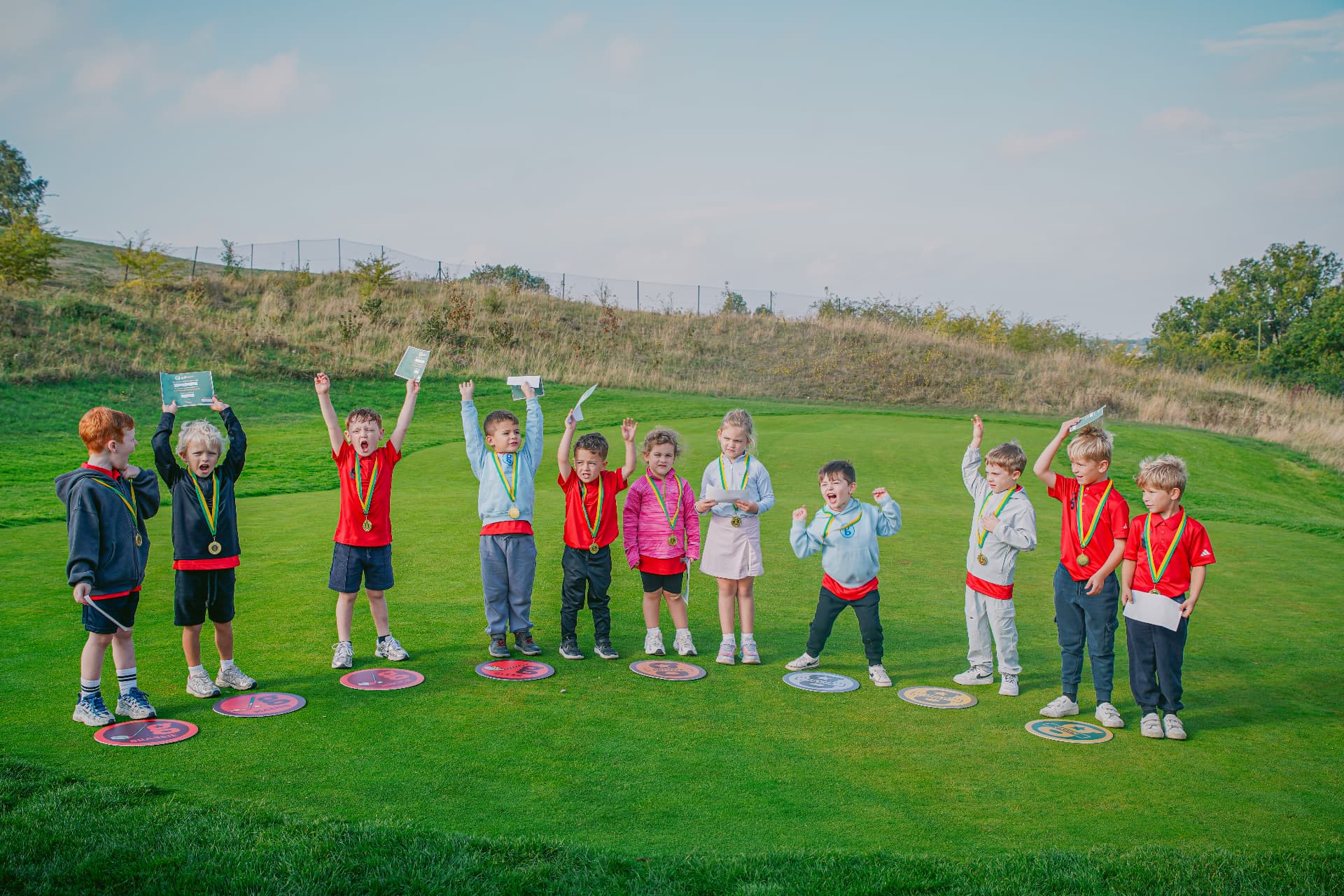 Young Golfstars celebrating with medals and certificates on the green