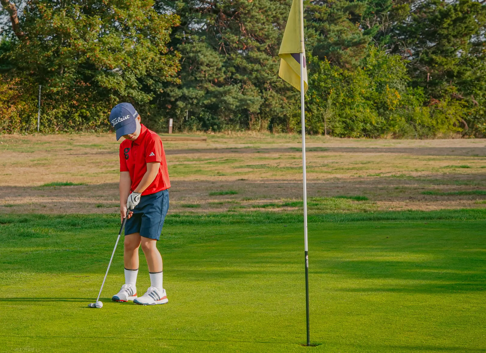 Risingstars player in red putting towards the flag