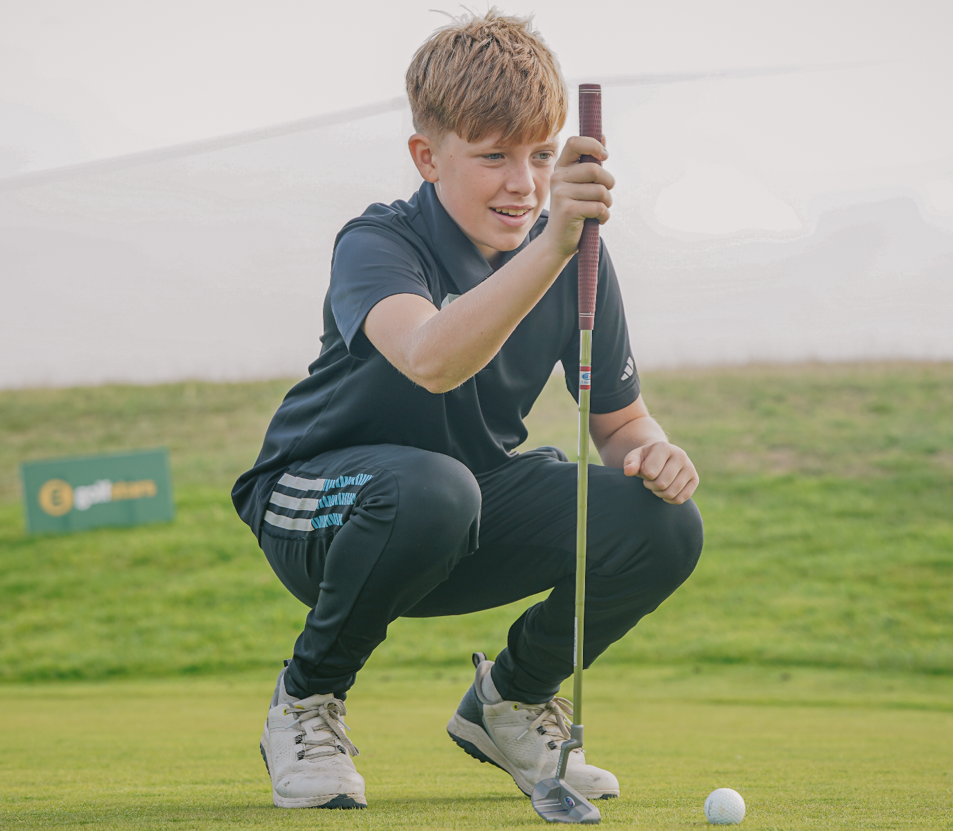 A golfstars player in black lining up a putt on the course