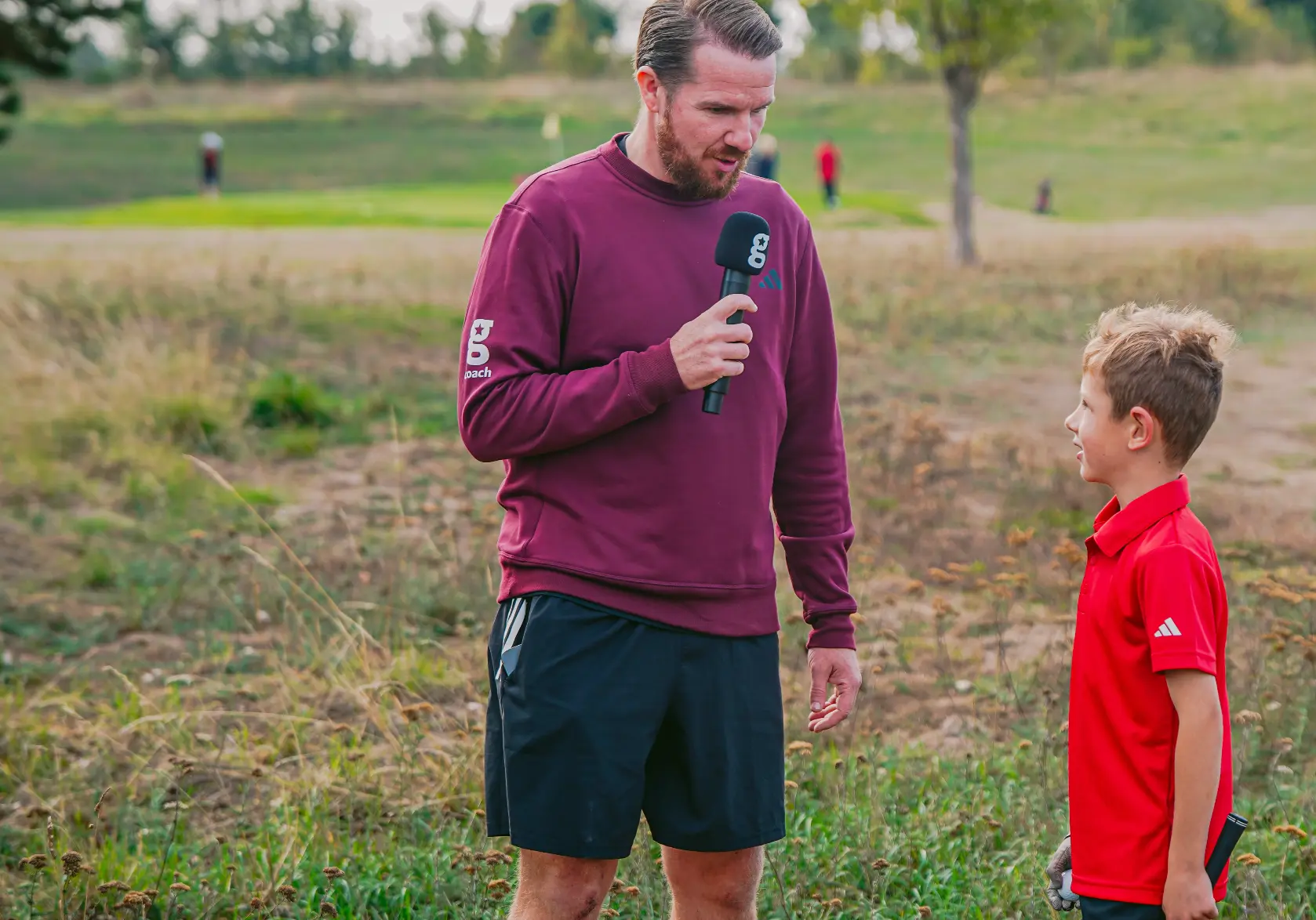 A Golfstars coach interviewing a young golfer on the course