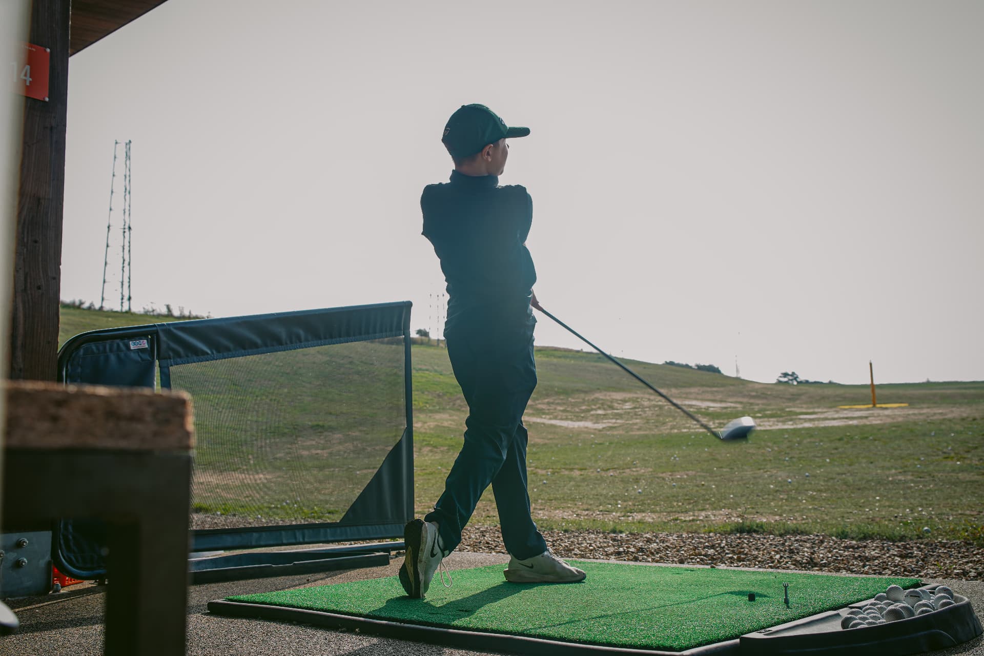 A young golfer following through on a drive at the range