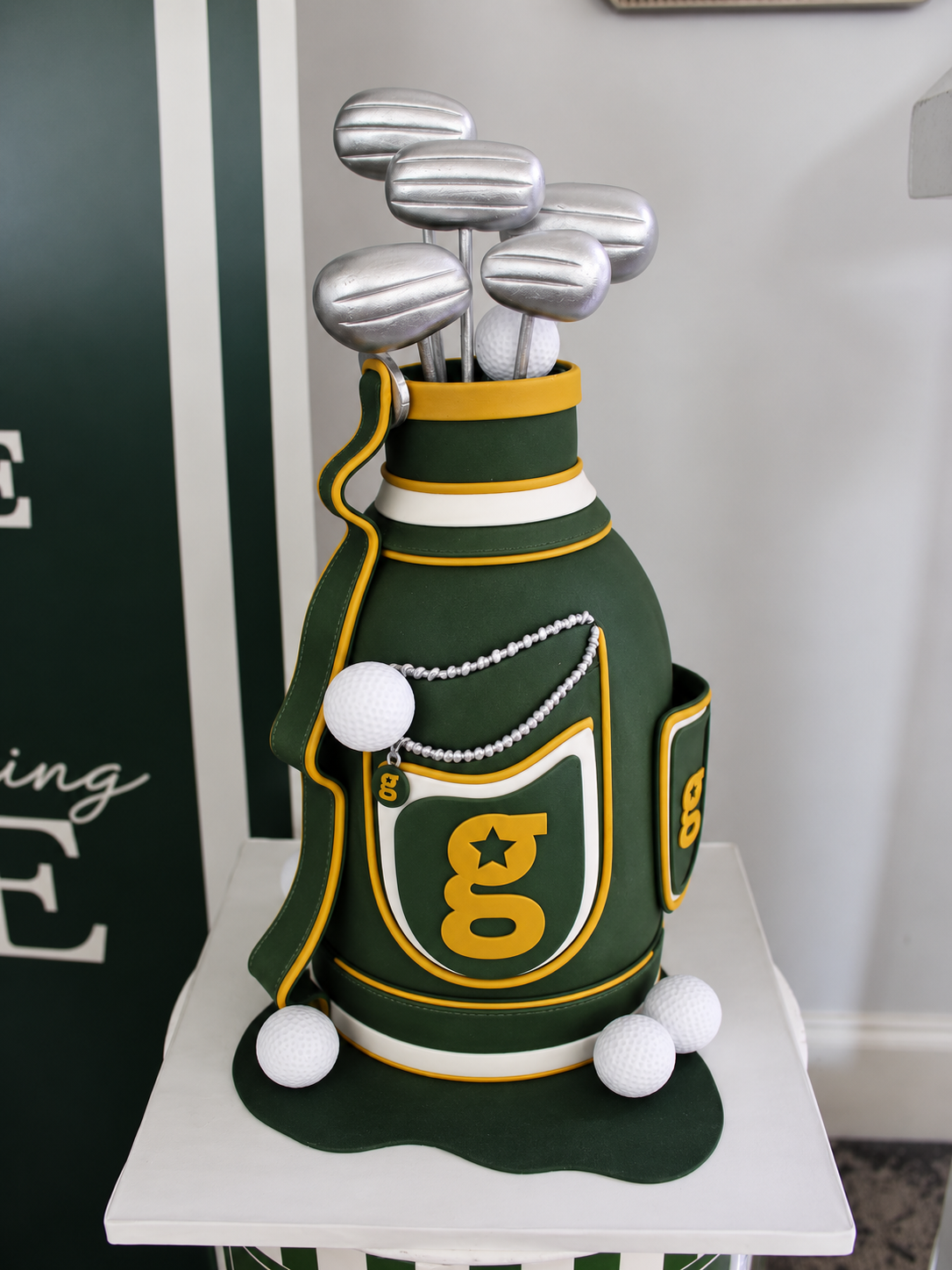 A green and gold Golfstars golf bag birthday cake with silver clubs and golf balls